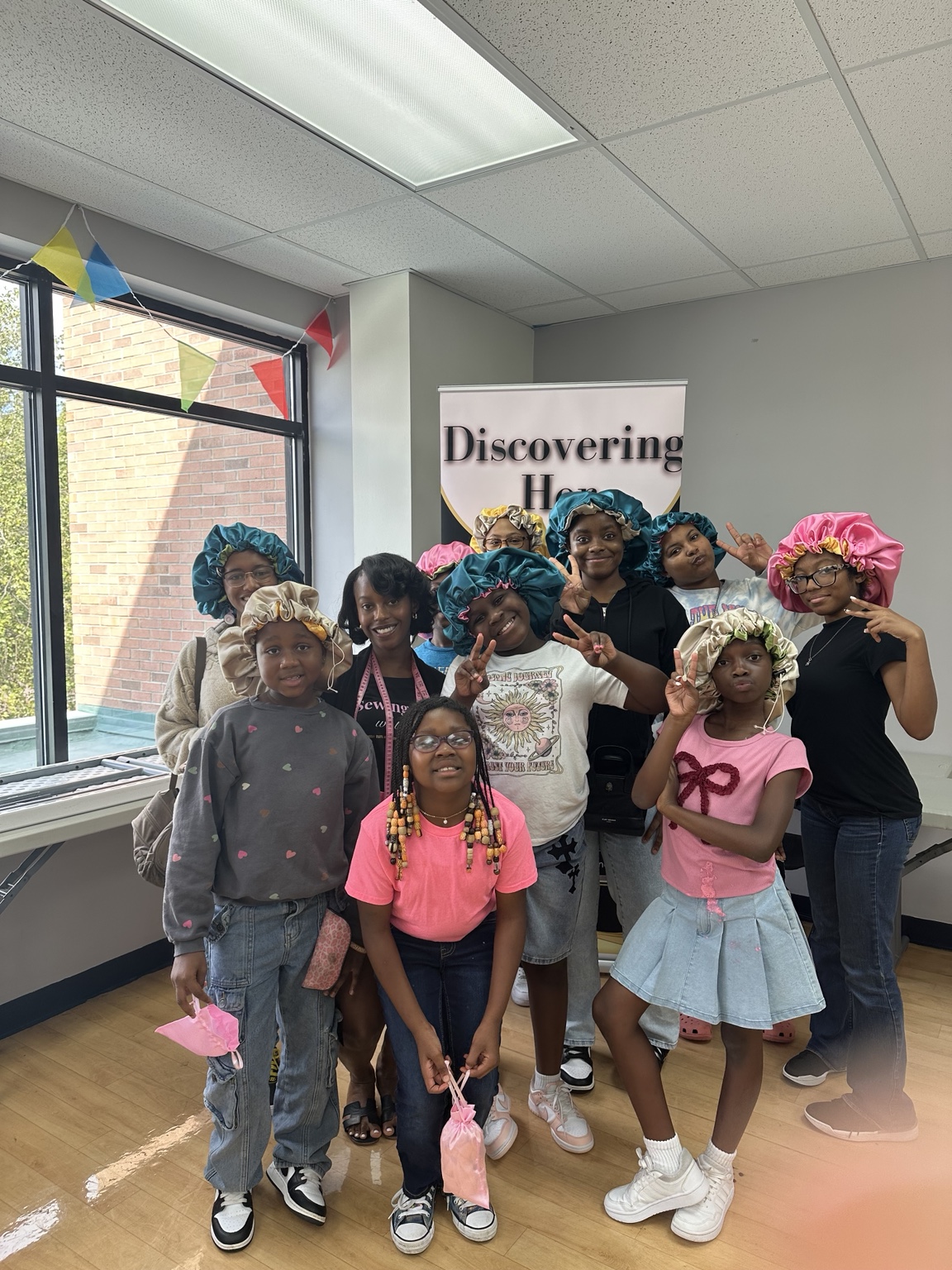 Discovering Her participants proudly wearing bonnets they made during a workshop