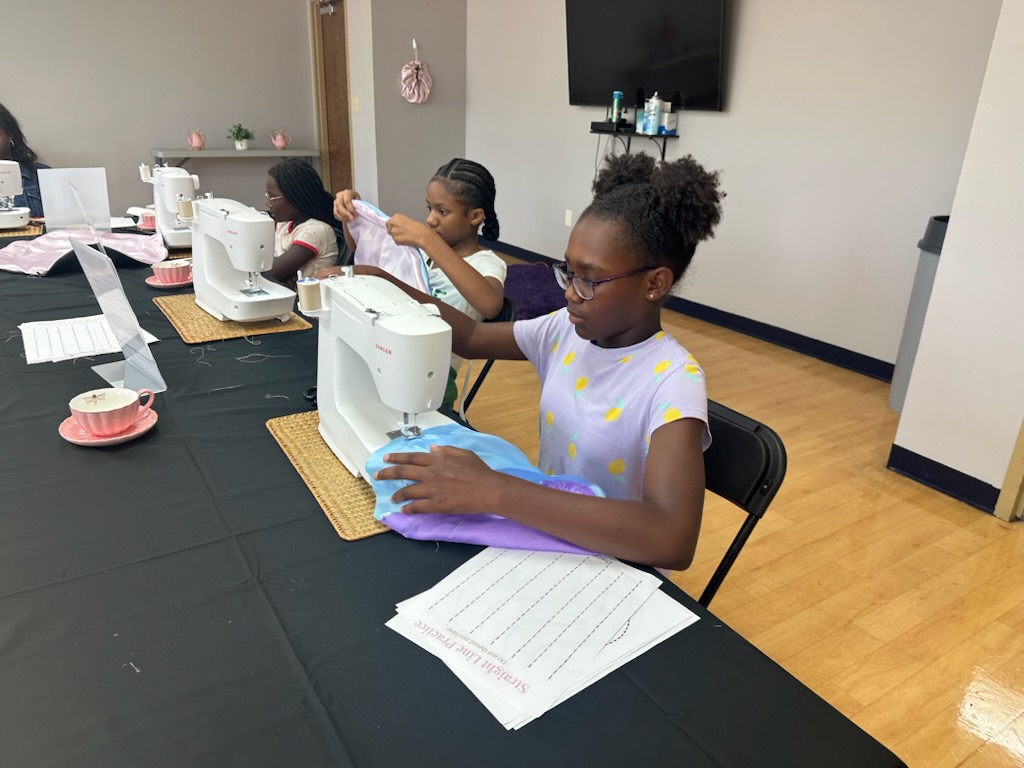 Mia helping a workshop participant sew her project